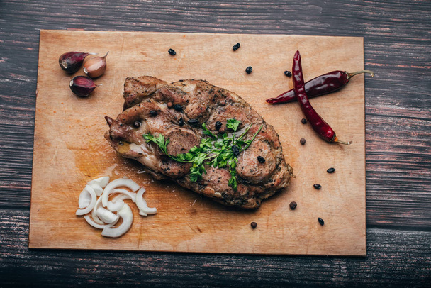 варене свиняче м'ясо на дерев'яній дошці з часником, цибулею, перцем
 - Фото, зображення