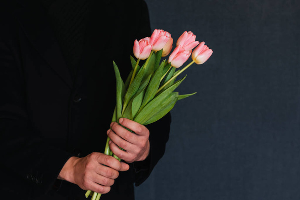 Strauß rosa Tulpen in den Händen eines Mannes - Foto, Bild