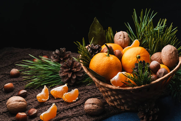 Tangerines, walnuts and hazelnuts decorated with pine cones and branches - Foto, imagen