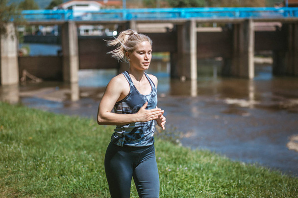 Photo of young blonde girl wearing sportswear running in the nature - Photo, Image