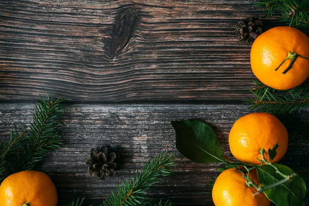 Christmas background with Mandarins, fir branches and pine cones. Winter holiday frame with cinnamon, star anise and copy space. Flat lay top view - Foto, afbeelding