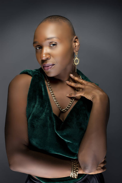 Beautiful black African American female model posing confidently with bald hairstyle in a studio.  The woman is wearing stylish fashion and portraying uniqueness and individuality.   - Photo, image