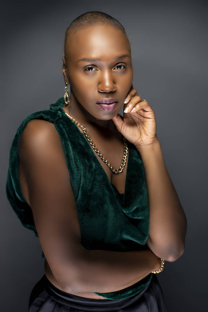 Beautiful black African American female model posing confidently with bald hairstyle in a studio.  The woman is wearing stylish fashion and portraying uniqueness and individuality.   - Фото, зображення