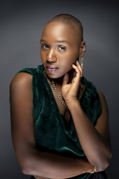Beautiful black African American female model posing confidently with bald hairstyle in a studio.  The woman is wearing stylish fashion and portraying uniqueness and individuality.   - Fotoğraf, Görsel