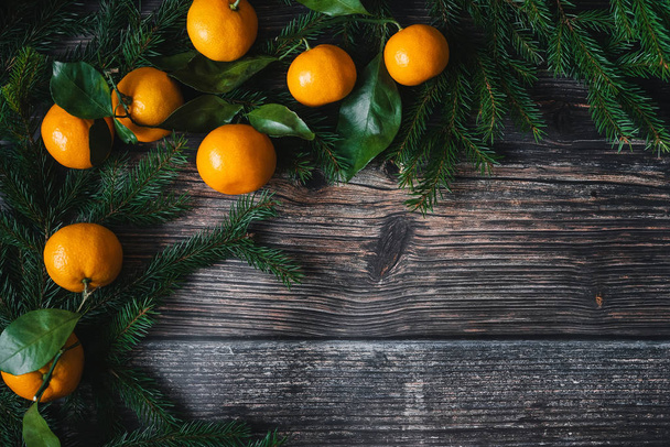 tangerines and fir branches on wooden background for Christmas holiday. - Photo, Image