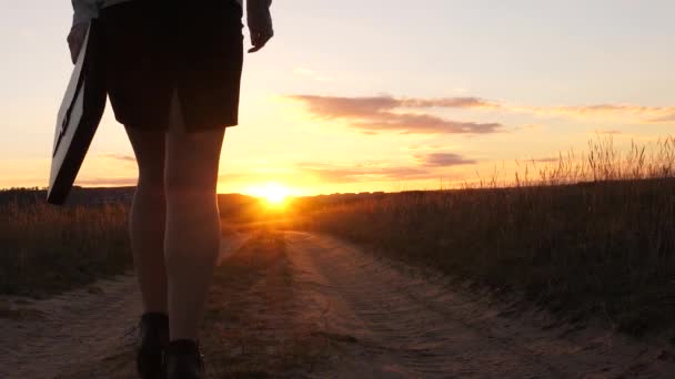 Een zakenvrouw wandelingen langs een landweg met een tablet in haar hand, de miertsaet van de zon tussen womens benen. sexy zakelijke vrouw meisje uitgevoerd op het platteland. sexy meisje reist op het platteland - Video