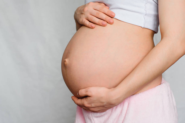 вагітна дівчина ніжно обіймає живіт
 - Фото, зображення