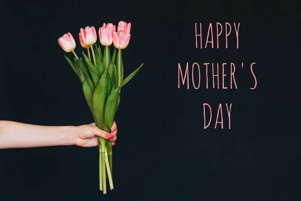 Carte de voeux avec l'inscription joyeuse fête des mères. Bouquet de fleurs roses de tulipes dans la main d'une femme
 - Photo, image