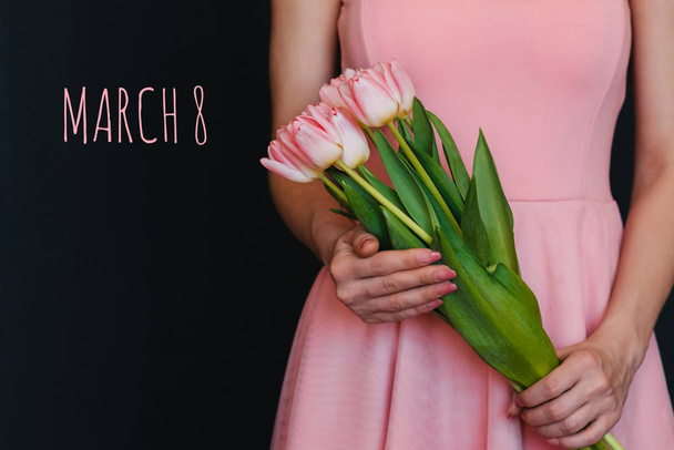 bouquet of flowers of pink tulips in the hands of a girl. Greeting card with text March 8 - Photo, Image
