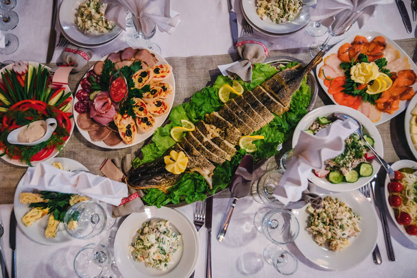 レストランでお祝いのテーブルの上に焼きパイクやその他の軽食と伝統的なロシア料理 - 写真・画像