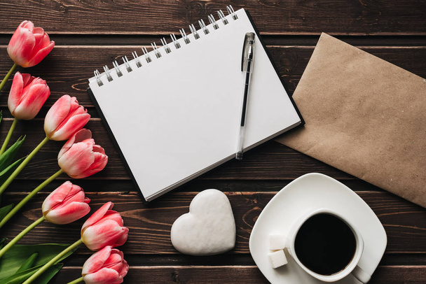 Strauß rosa Tulpenblüten und eine Tasse Kaffee auf einem hölzernen braunen Tisch - Foto, Bild