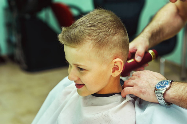 Barbeiro masculino faz o menino de corte na cabine
 - Foto, Imagem