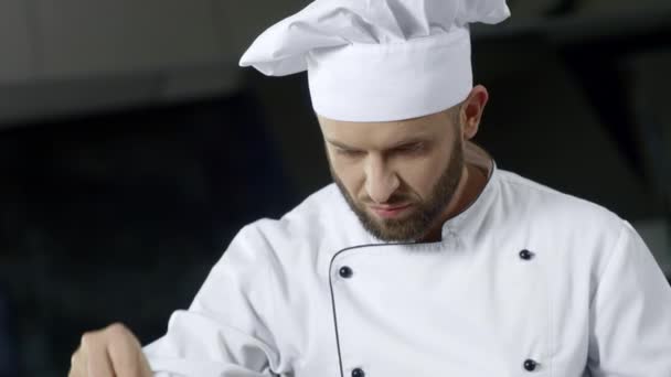 Porträt des Küchenchefs in der professionellen Küche. ernsthafter Koch salzt Essen. - Filmmaterial, Video