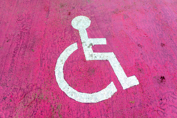 A mozgássérült parkoló szimbóluma a rózsaszín padlóhoz úton - Fotó, kép
