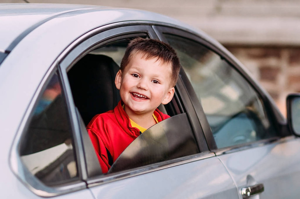 a laughing child looks out of an open car window - Foto, Imagem