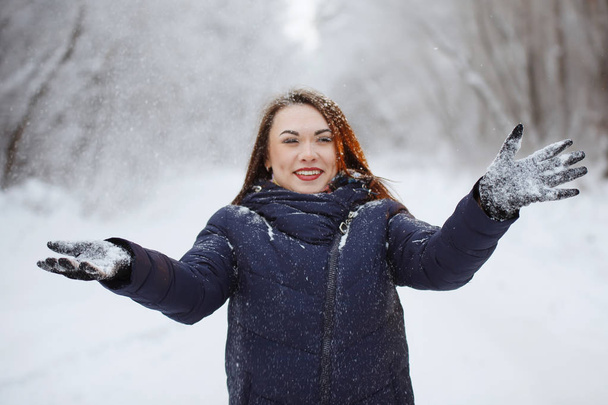 Młoda, ładna kobieta w niebieskim szaliku i kurtce w śnieżnym lesie. - Zdjęcie, obraz