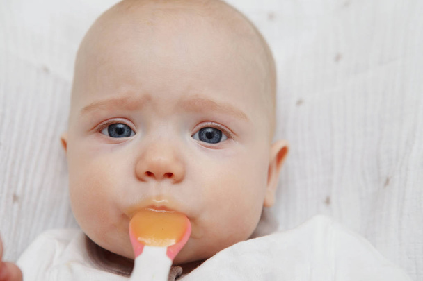Όμορφη υπέροχο μωρό πέντε μηνών κορίτσι τρώει με κουτάλι. Υγιεινά τρόφιμα. Μητρική φροντίδα. Φροντίδα των παιδιών. Γκρο πλαν. - Φωτογραφία, εικόνα