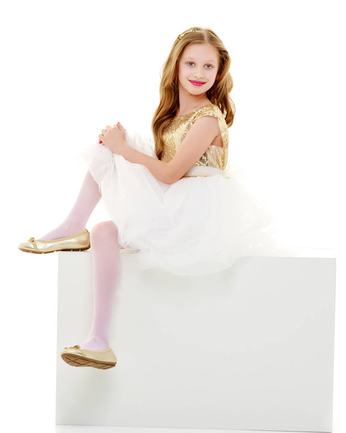 The little girl is sitting on a white banner. - Valokuva, kuva