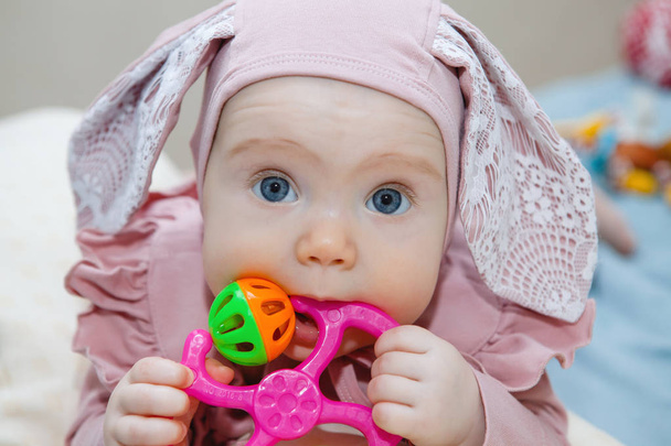 Portret van een schattige baby in een roze hoed met oren. - Foto, afbeelding