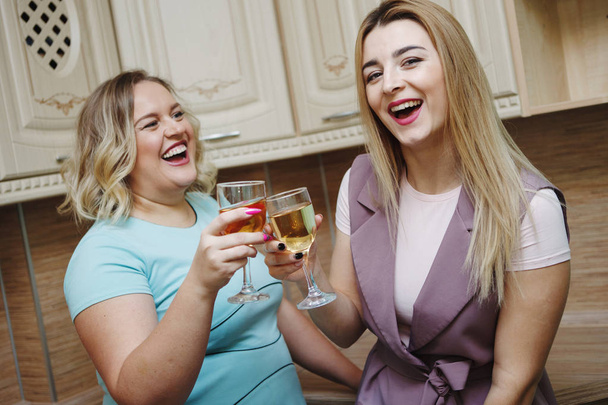 Deux copines femmes dans la cuisine s'amusent et boivent du vin
. - Photo, image