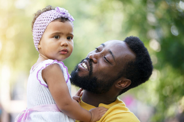 African father holds his little daughter in his arms, hugs and k - 写真・画像