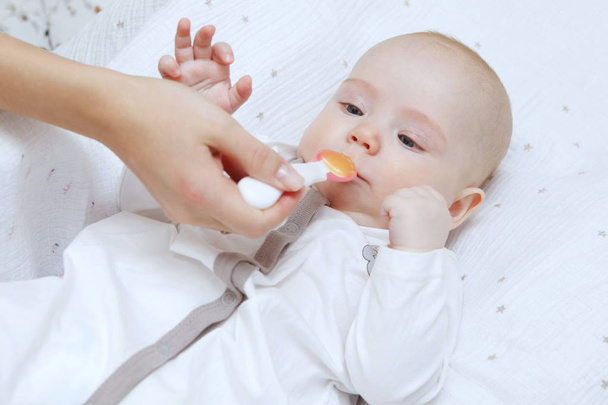 Prachtige mooie vijf maanden durende babymeisje eten met een lepel. Gezonde voeding. Moederlijke zorg. Kinderopvang. Close-up. - Foto, afbeelding