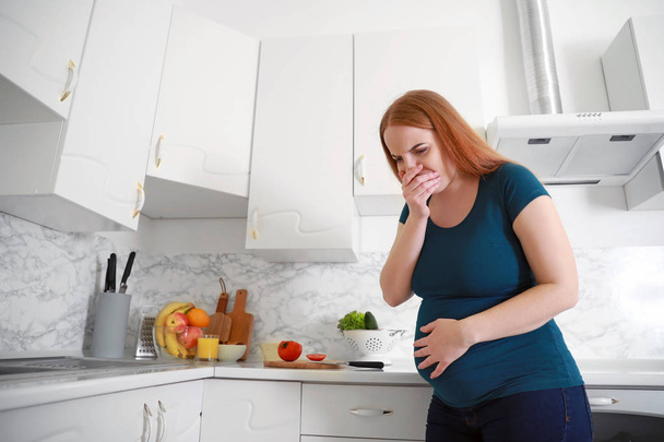 молода вагітна жінка, що страждає токсикозом на кухні
 - Фото, зображення