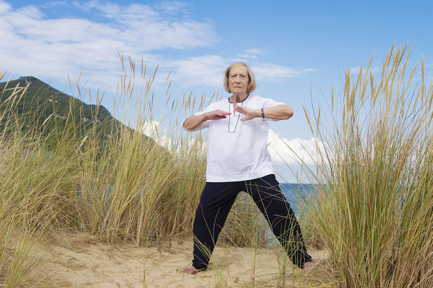 Старшая женщина, практикующая Тай Чи на пляже
  - Фото, изображение