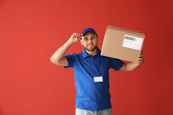 Handsome delivery man with box on color background - Photo, Image