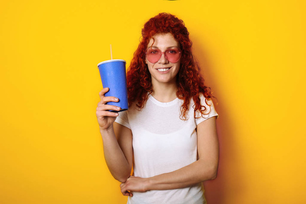 色の背景に飲み物を持つ美しい赤毛の女性 - 写真・画像