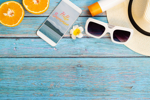 Belas férias de verão, acessórios de praia, laranja, óculos de sol, chapéu, protetor solar e smartphone em fundos de madeira - Foto, Imagem
