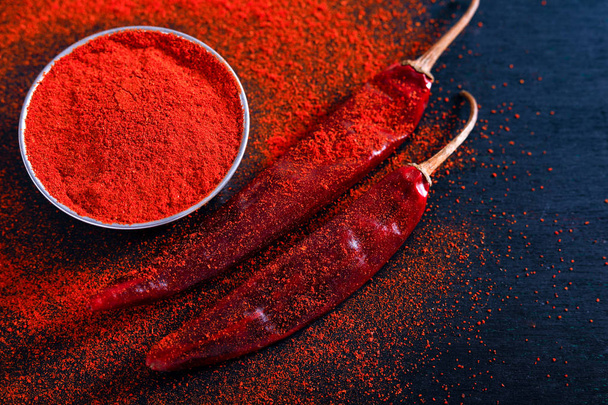 Red Chili pepper flakes and chili powder burst on black background - Foto, Imagen