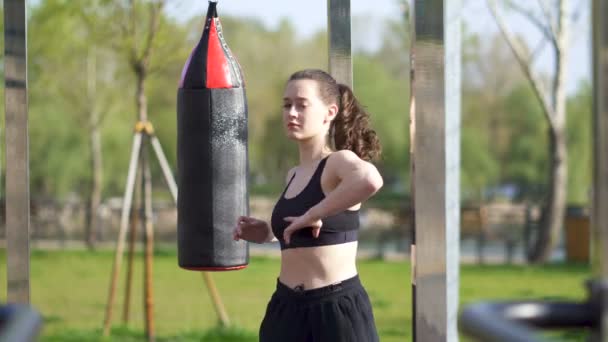 4k.Young woman boxer, kickboxer warm body on street training ground. - Footage, Video