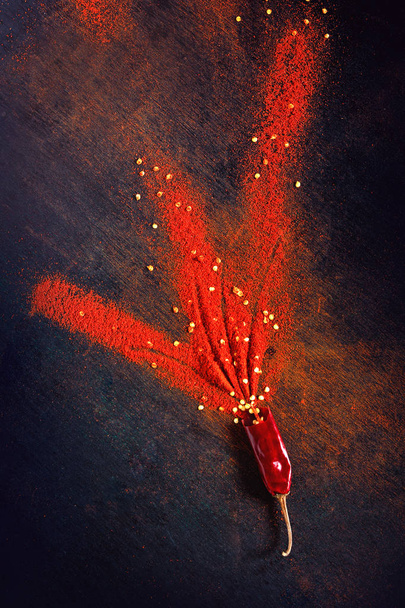Red Chili pepper flakes and chili powder burst on black background - Fotó, kép