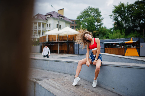 Sexy curly model girl in red top, jeans denim shorts, eyeglasses - Фото, зображення