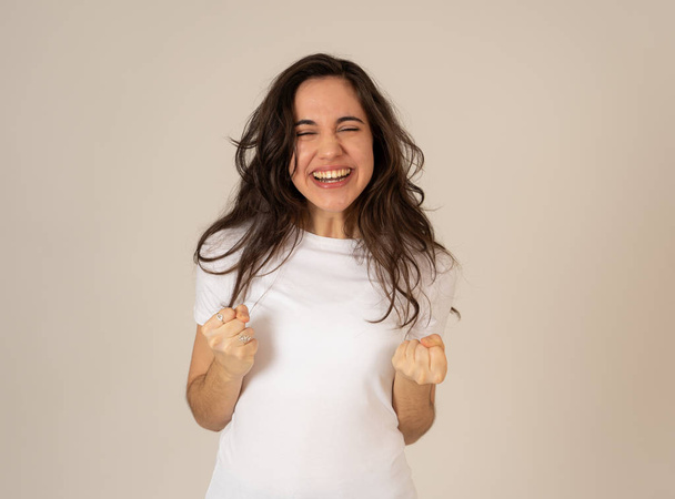 Young attractive latin woman celebrating success winning or feeling lucky and joyful dancing making celebration gestures with arms. Isolated on neutral background In People expressions and emotions. - Photo, image