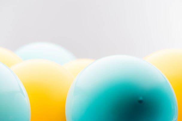 Close up view of blue and yellow balloons isolated on grey - Фото, изображение
