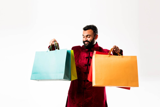 Indian Young man shopping while wearing red traditional wear, standing isolated over white background - Zdjęcie, obraz