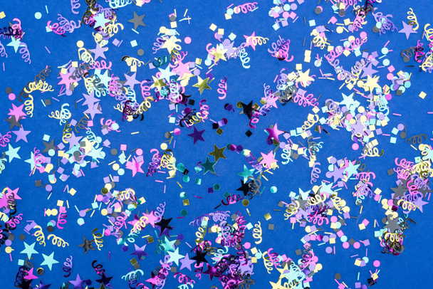 Top view of colorful sparkling confetti on blue background - Φωτογραφία, εικόνα