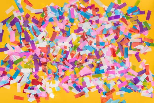 Vue du dessus des confettis colorés sur fond de fête jaune
  - Photo, image