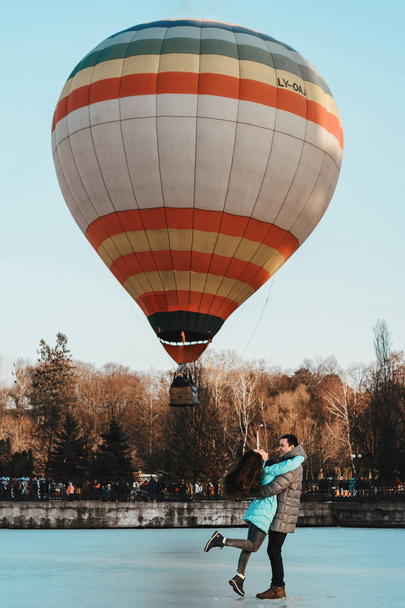 Mladá dívka s chlapcem stojící na ledu na pozadí balónu v parku. - Fotografie, Obrázek