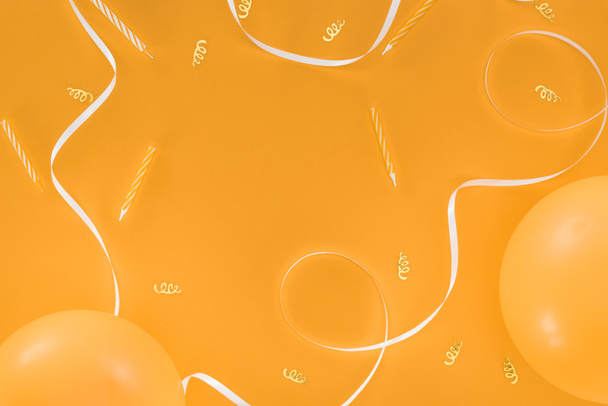 White ribbon and gold confetti and candles on orange background - Photo, Image