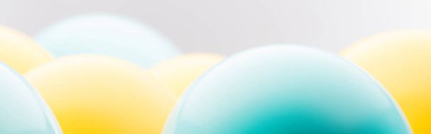 Panoramic shot of blue and yellow balloons isolated on grey  - Foto, Bild