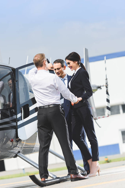 businesspeople in formal wear near helicopter and Pilot - 写真・画像