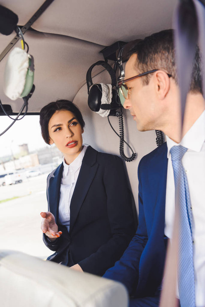 selective focus of businesswoman and businessman sitting in helicopter cabin - Foto, Bild