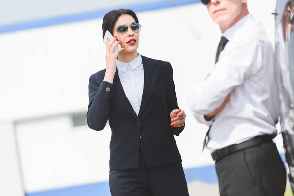 selective focus of businesswoman talking on smartphone near man - Photo, Image