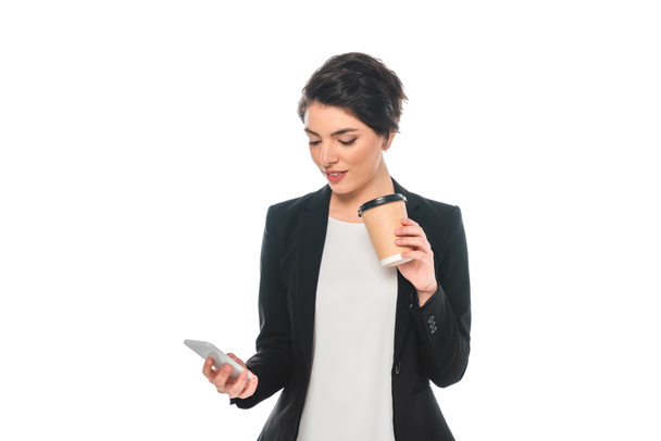 mooie gemengde race zakenvrouw met behulp van smartphone en koffie drinken uit wegwerp beker geïsoleerd op wit - Foto, afbeelding