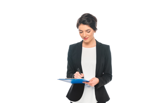 attractive mixed race businesswoman in formal wear writing on clipboard isolated on white - Foto, Bild