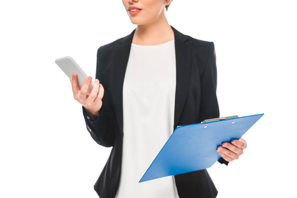 partial view of mixed race businesswoman using smartphone and holding clipboard isolated on white - Fotografie, Obrázek