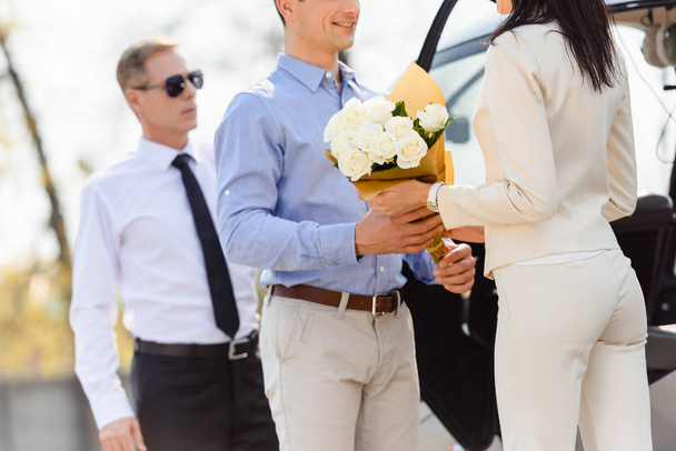 cropped view of husband giving flowers to wife on romantic date near helicopter and pilot - 写真・画像